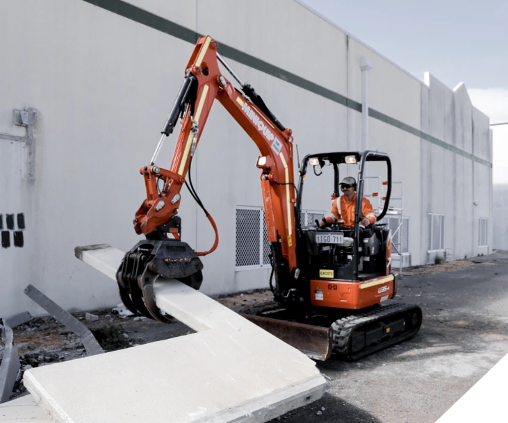A mini excavator being operated by a Slice It Right Staff as part of a commercial demolition project in Perth
